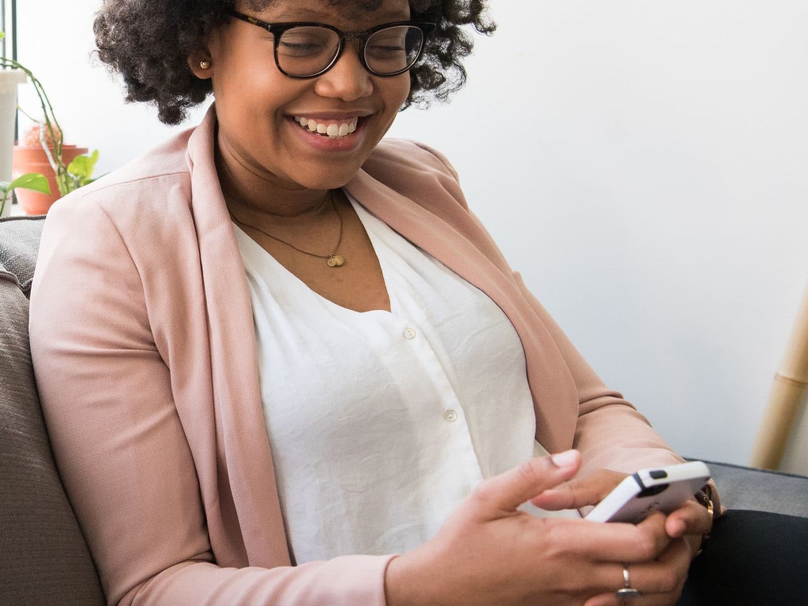 A patient sitting at home, laughing as she books on her phone