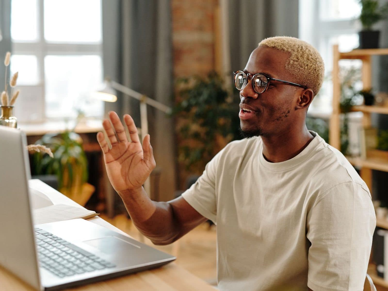 A patient at his kitchen table waving hello as his video session opens on the laptop