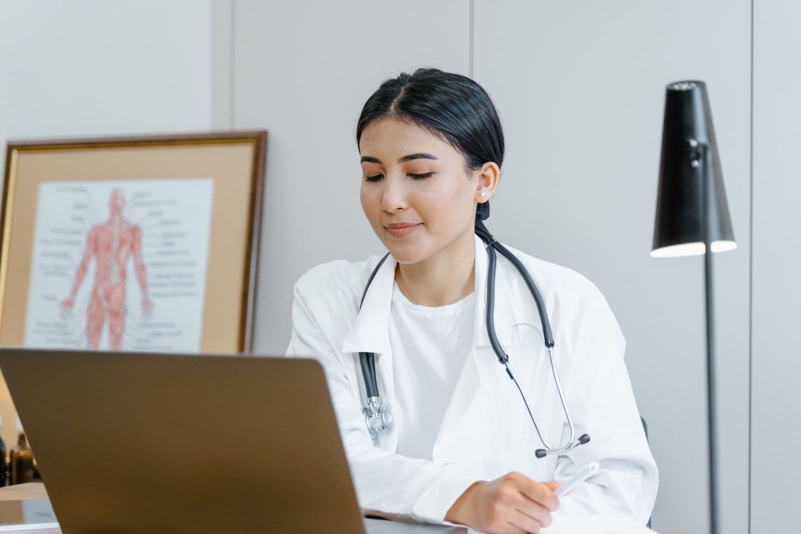 A physiotherapist at her laptop, answering a patient's questions on a call