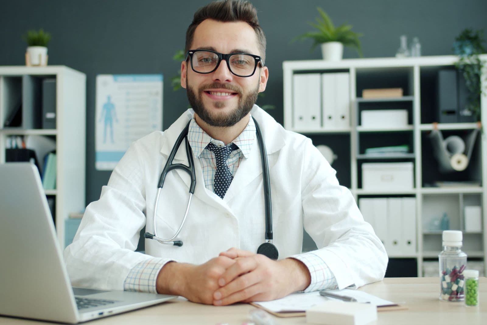 A physiotherapist smiling at his desk, ready to start a video session