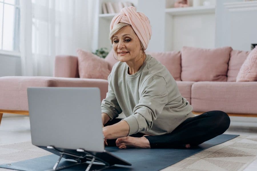 A couple following their exercise plan on mats at home, laptop open between them