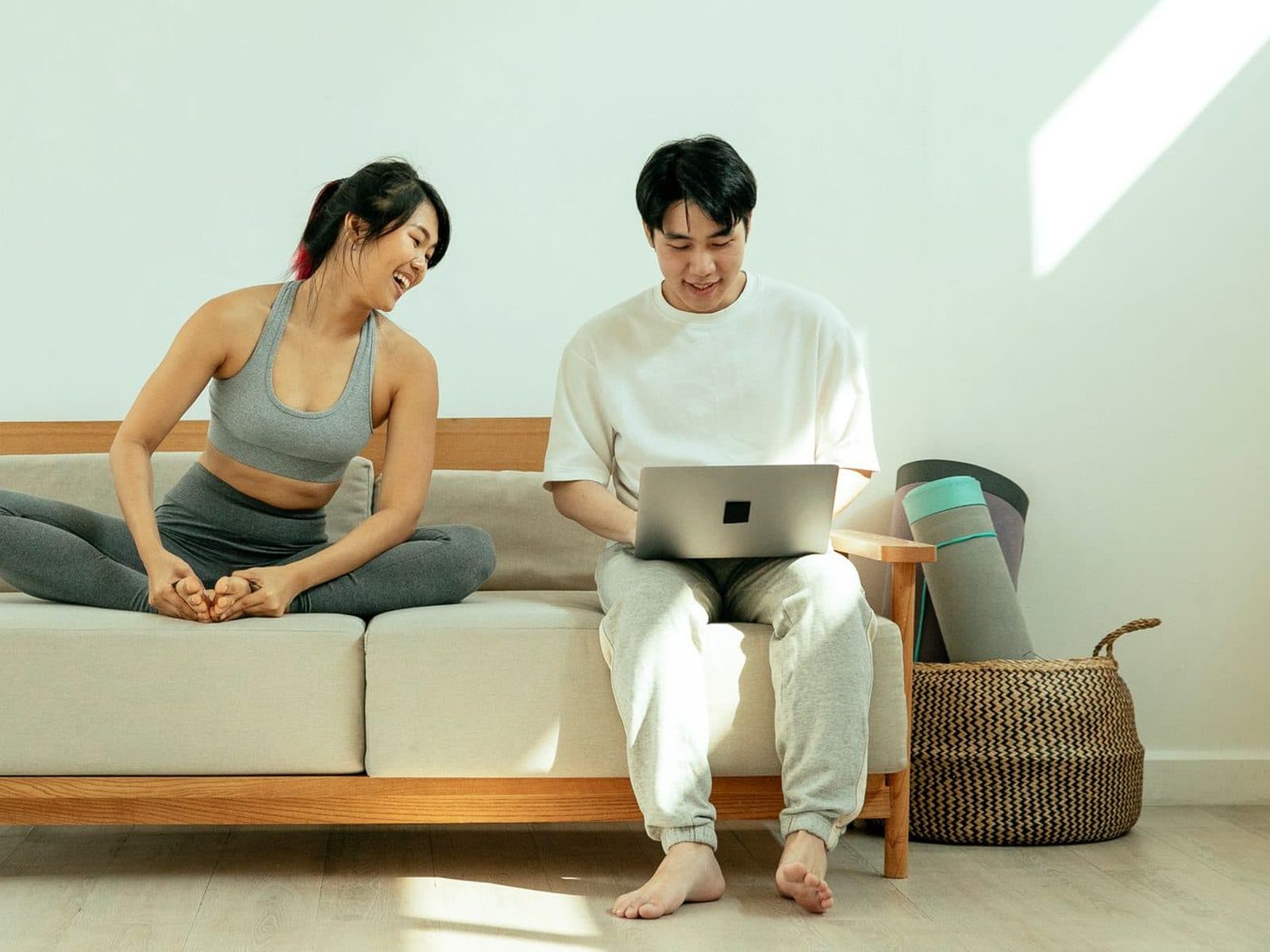 Two people on a sofa in a bright room, one following a session on a laptop