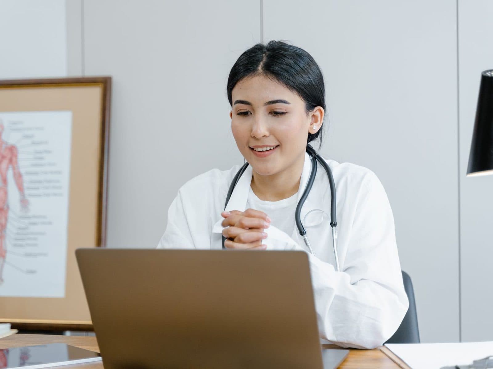 A physiotherapist smiling at her laptop as a session begins